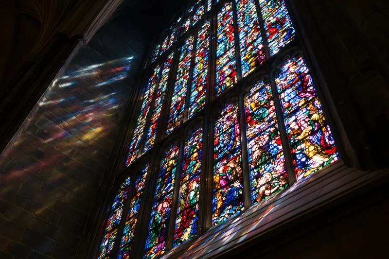Large gothic stained glass window glowing with light inside a cathedral interior