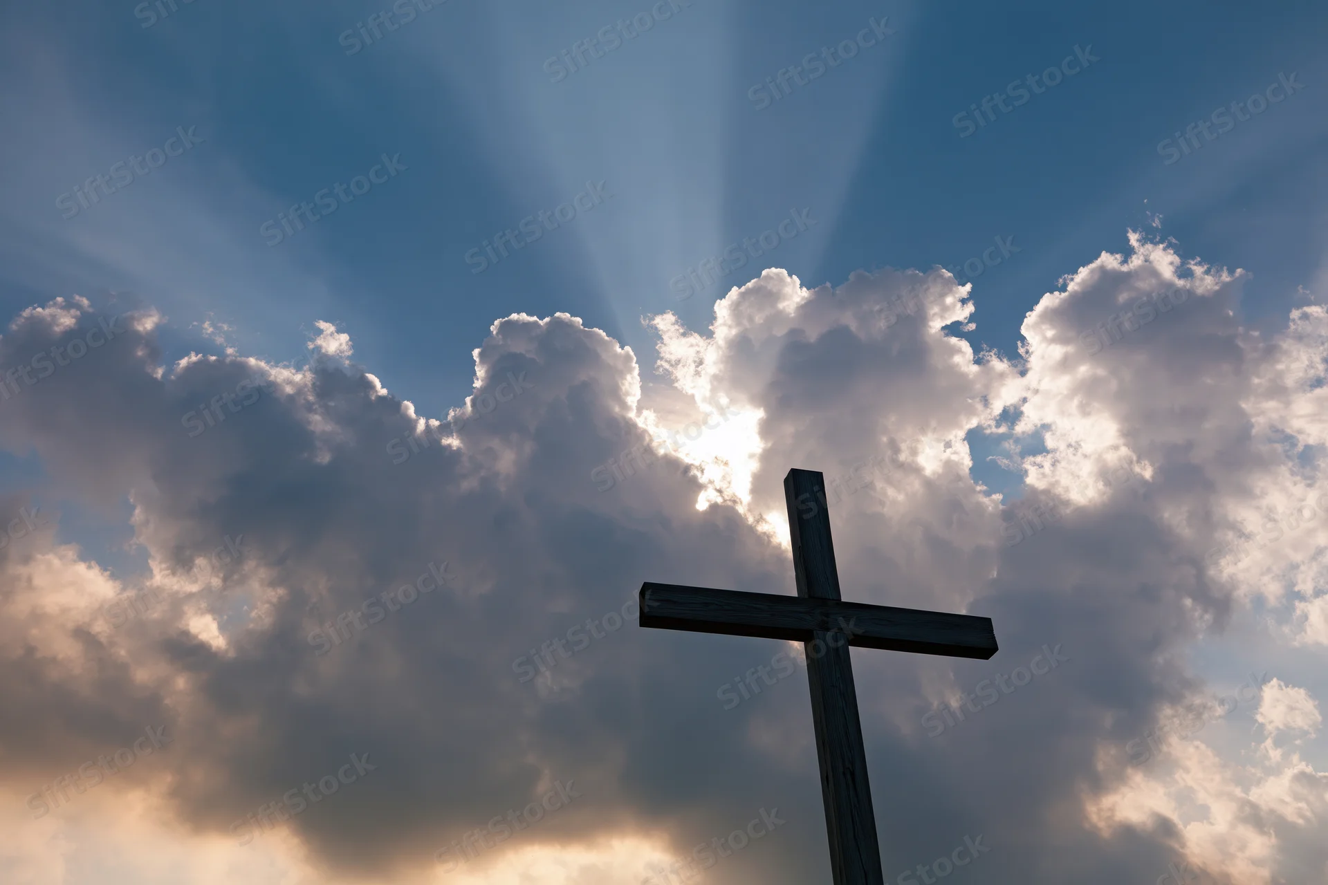 Wooden christian cross silhouetted against dramatic sky with sun rays through clouds