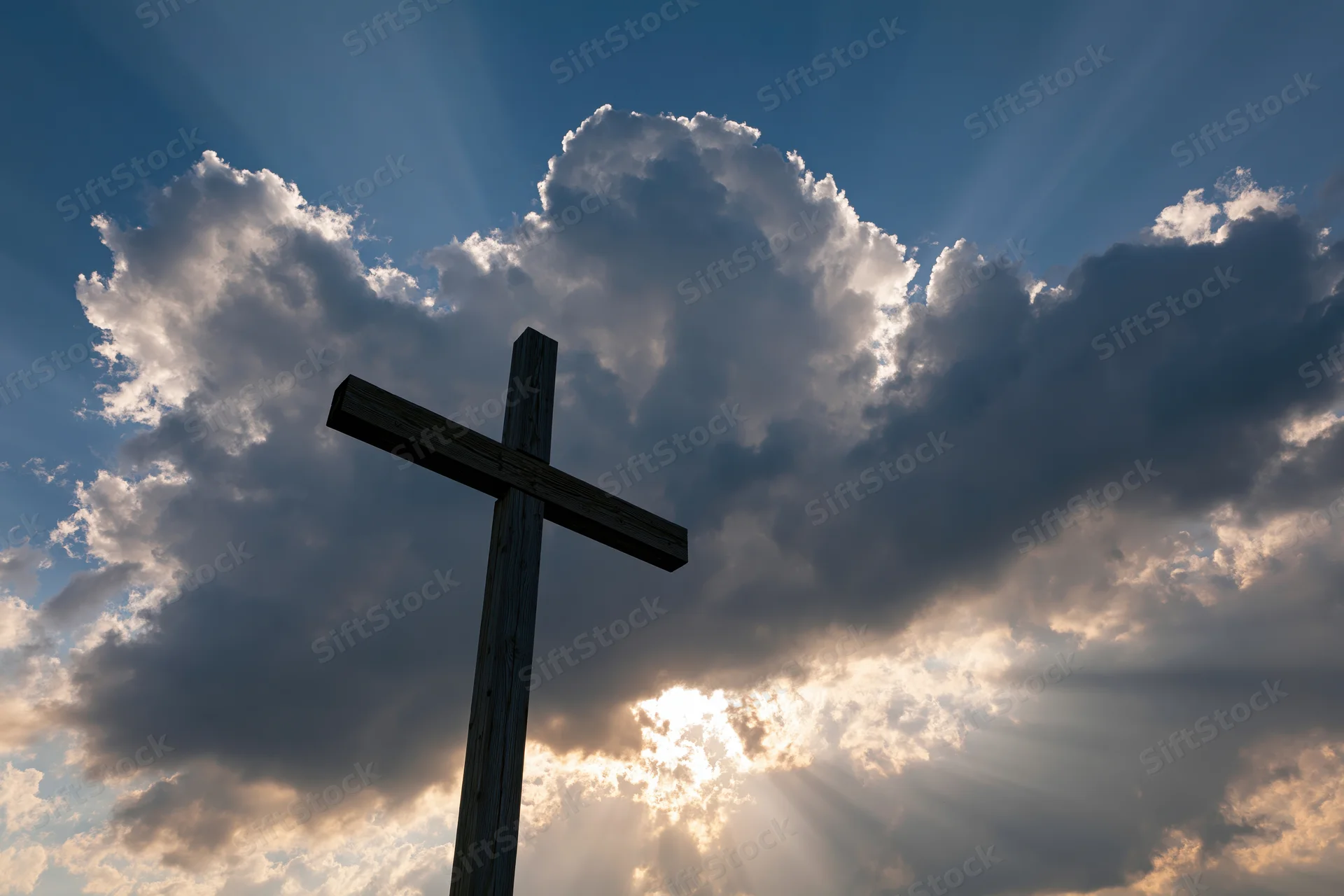 Wooden christian cross silhouetted against dramatic sky with sun rays through clouds