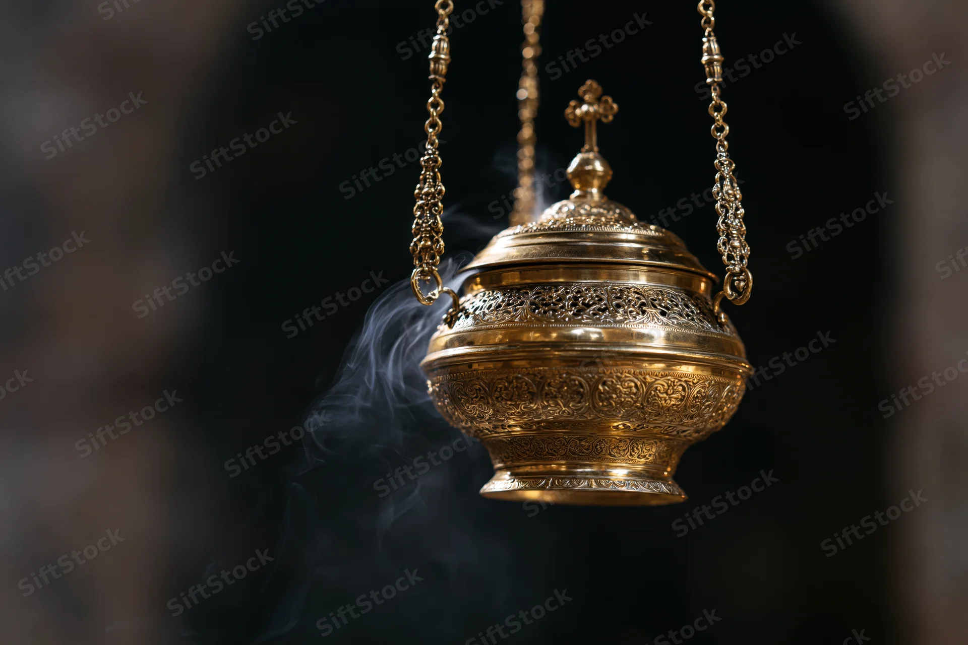 Ornate brass censer hanging with smoke rising from it in a church setting