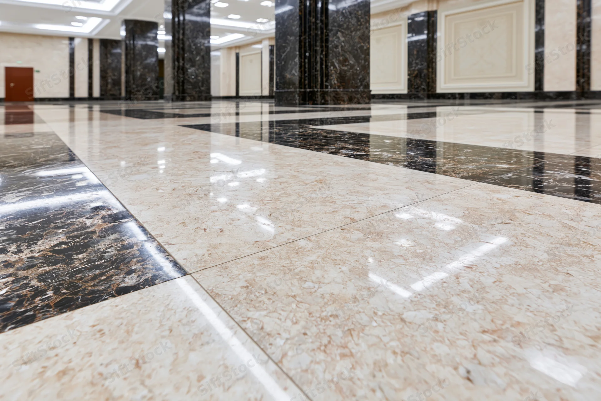 Polished marble floor in a spacious formal building lobby with reflective surfaces and columns