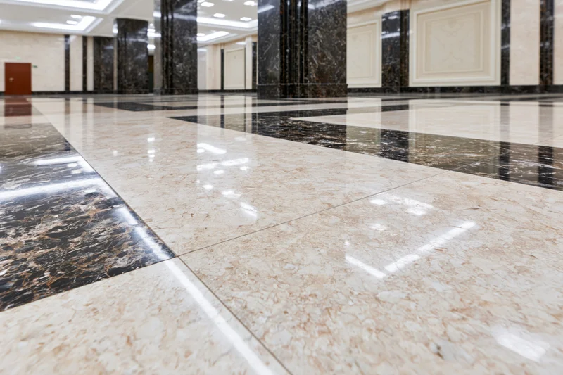Polished marble floor in a spacious formal building lobby with reflective surfaces and columns