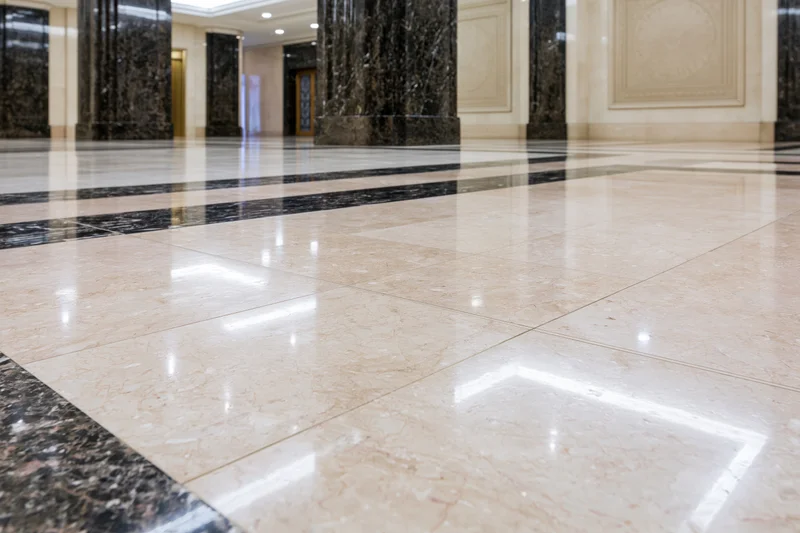 Polished marble floor in a formal building lobby with black columns and reflective surfaces
