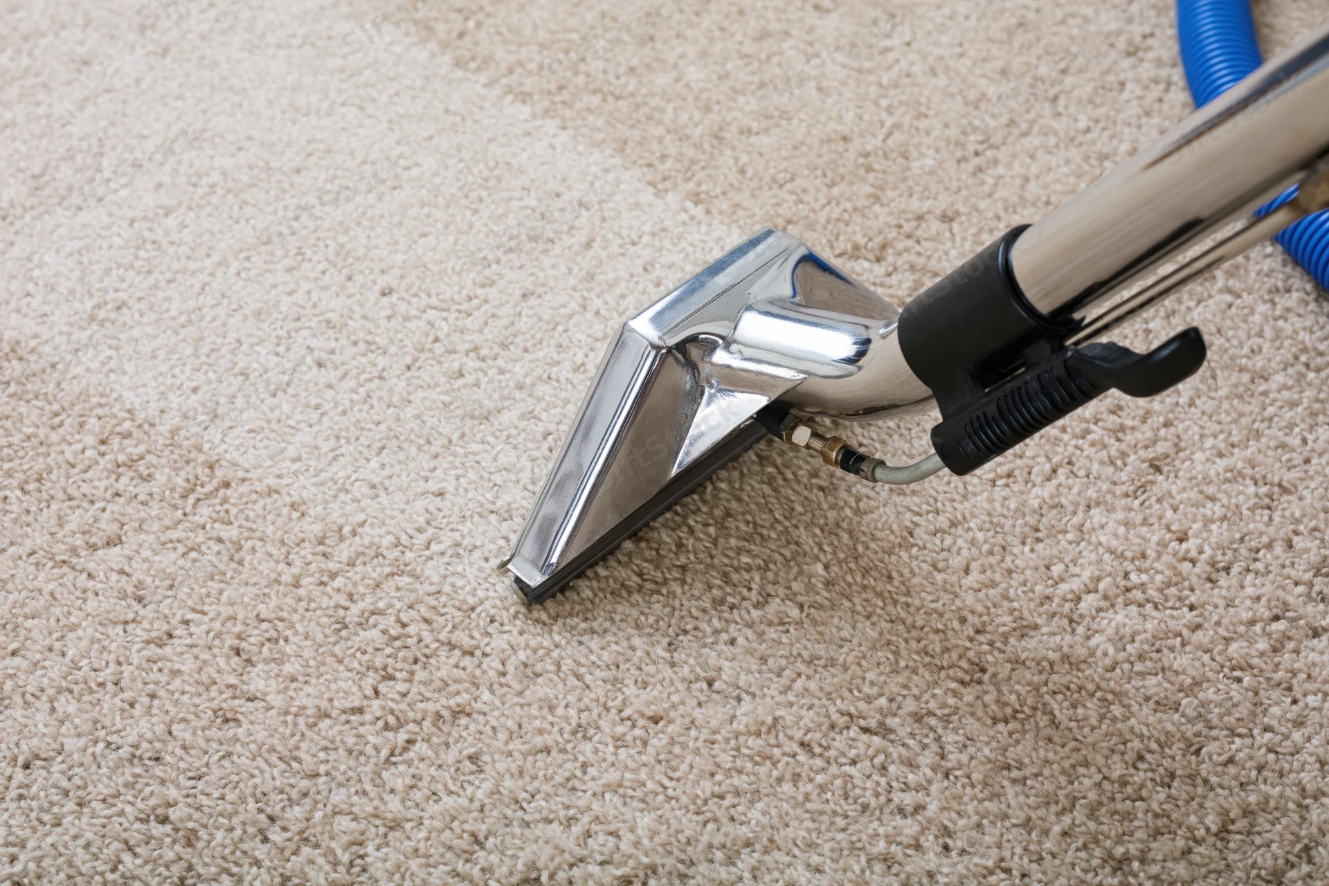 Carpet cleaning wand moving across beige carpet surface