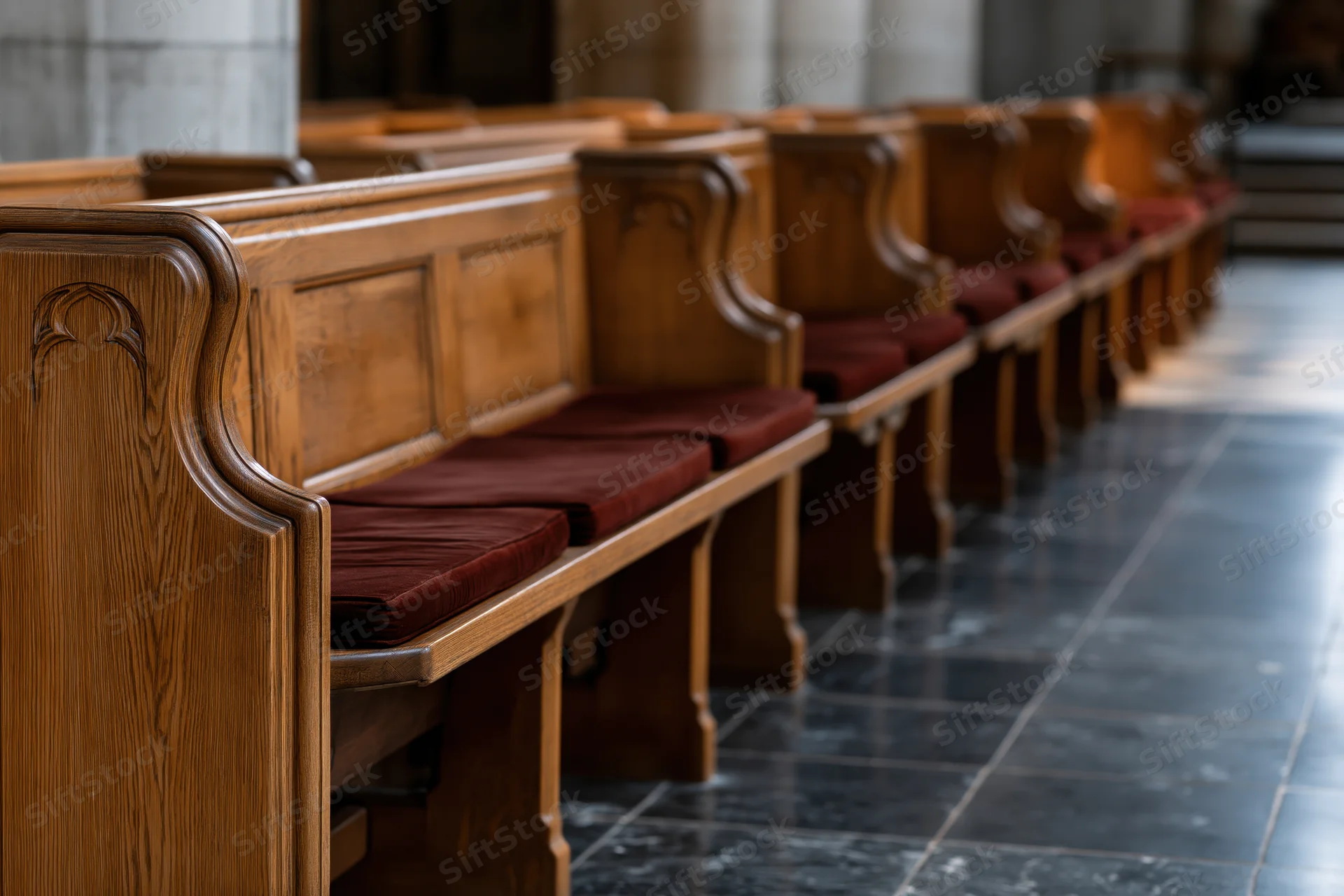 Rows of empty wooden church pews receding into the interior along a stone-tiled aisle