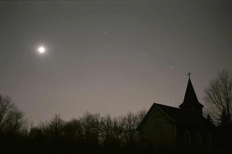 Wooden rural church silhouetted against full moon at night