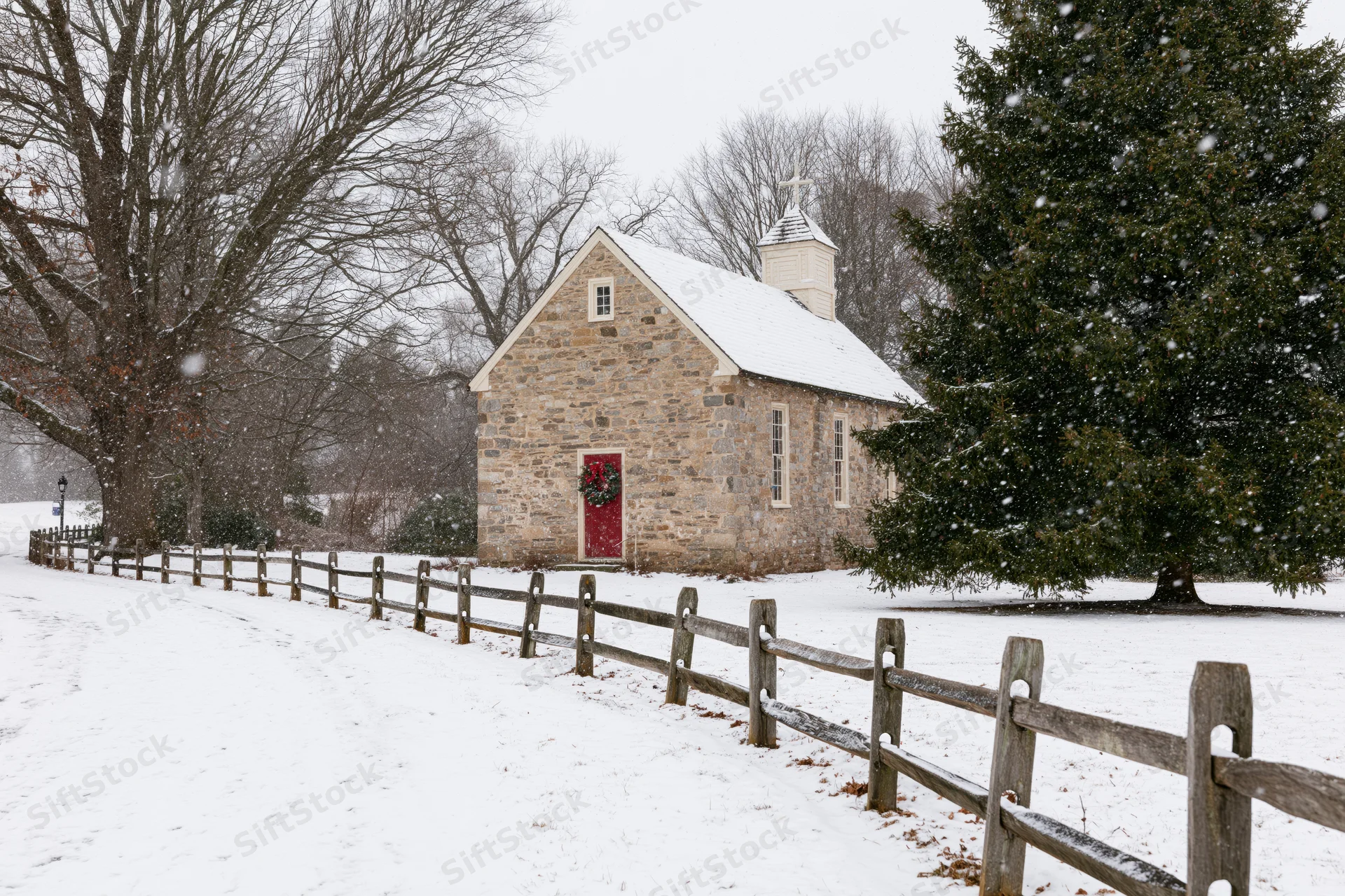 Small stone chapel with red door and christmas wreath in snowy rural landscape
