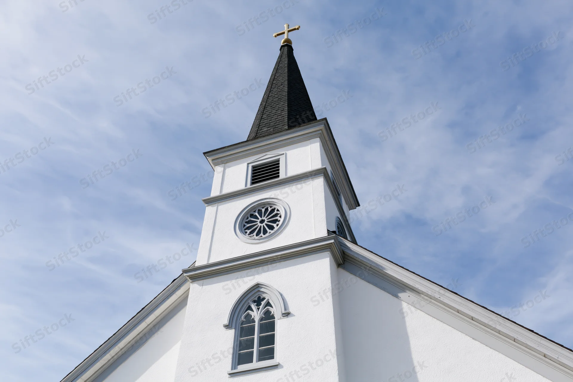 White protestant church facade with steeple and cross against blue sky