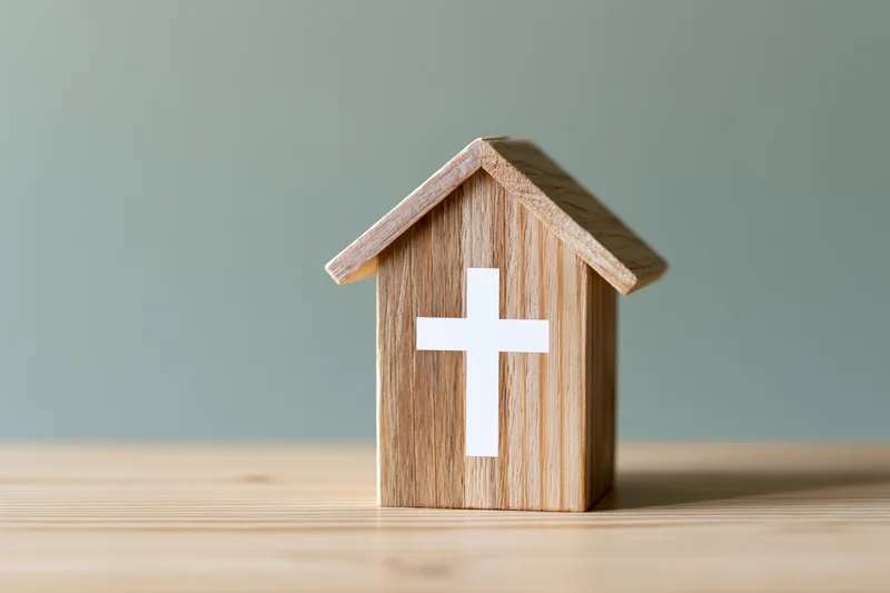 Wooden house block with white christian cross on front, placed on wooden surface