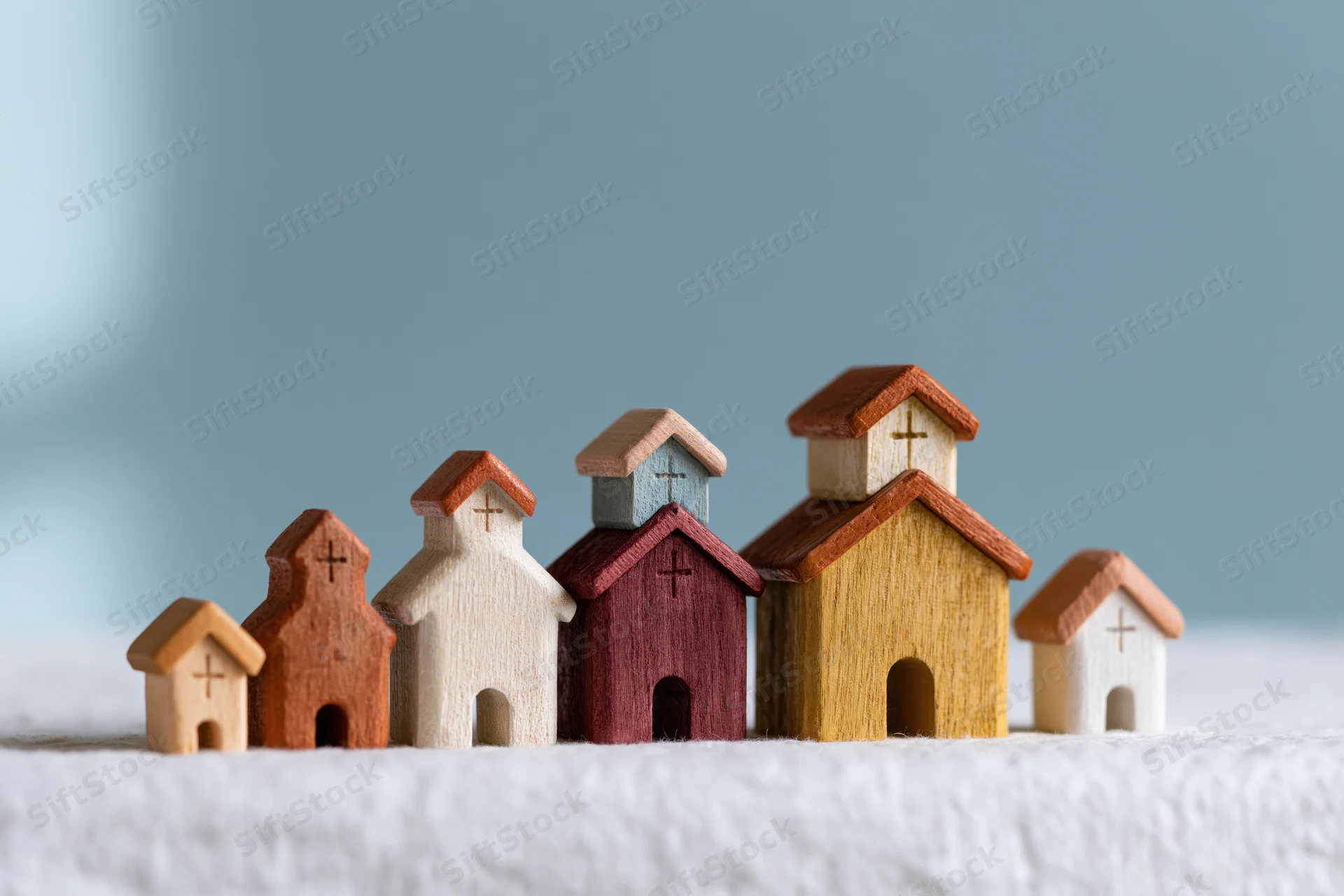 Small wooden church figurines arranged in a row on a white textured surface
