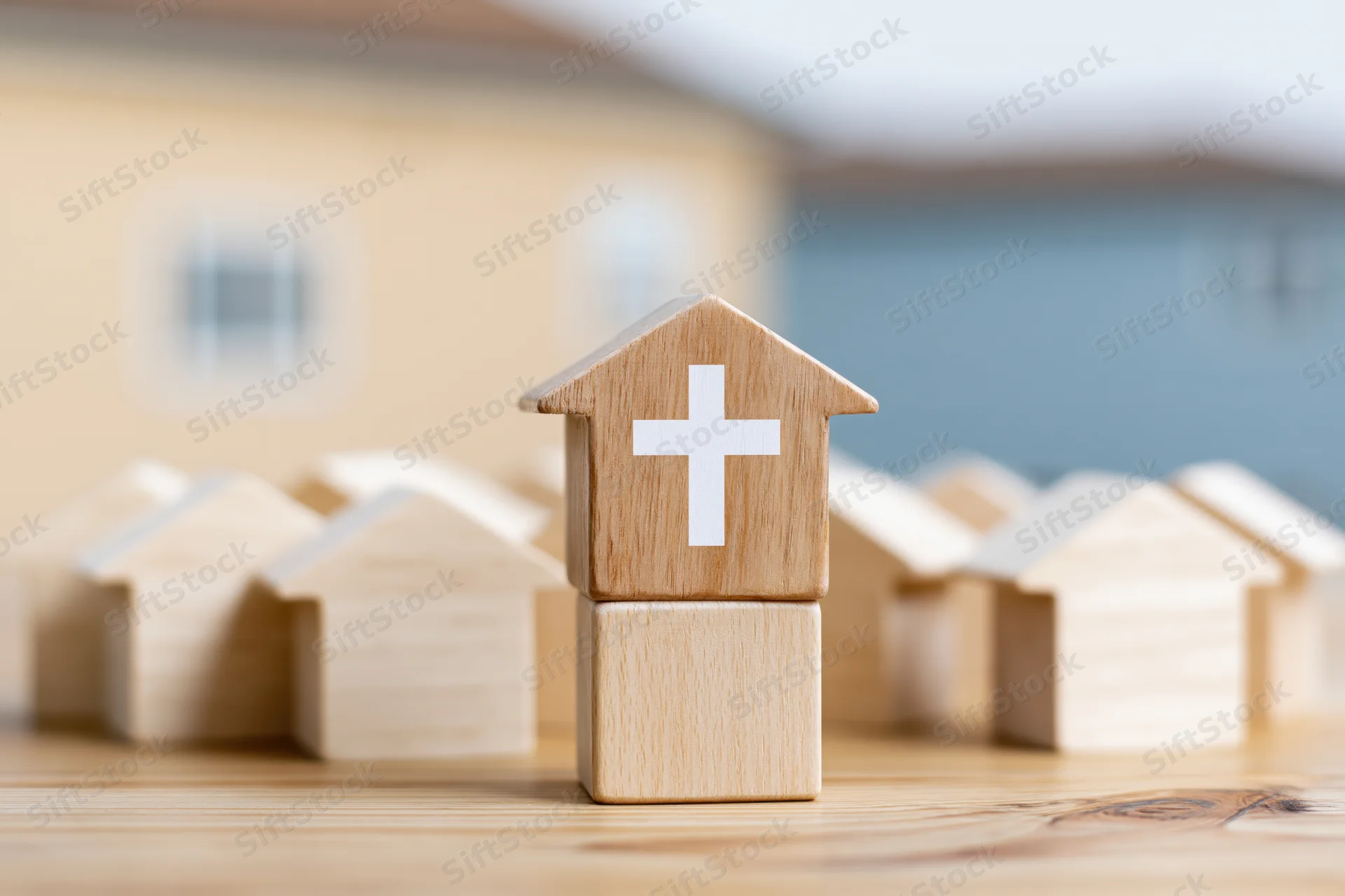 Wooden house blocks with a cross symbol arranged on a wooden surface