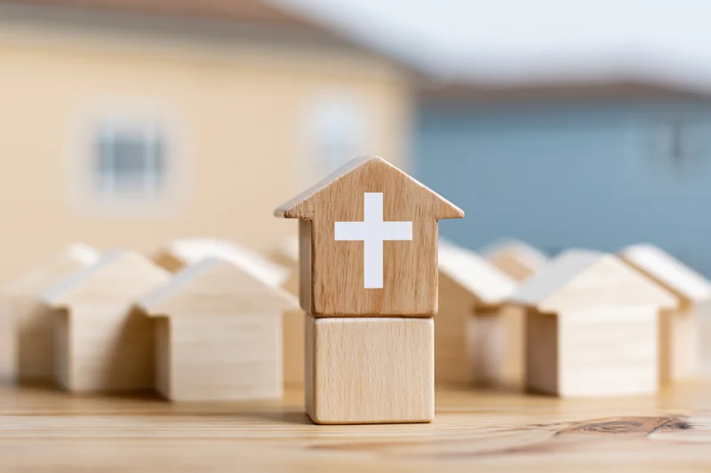 Wooden house blocks with a cross symbol arranged on a wooden surface