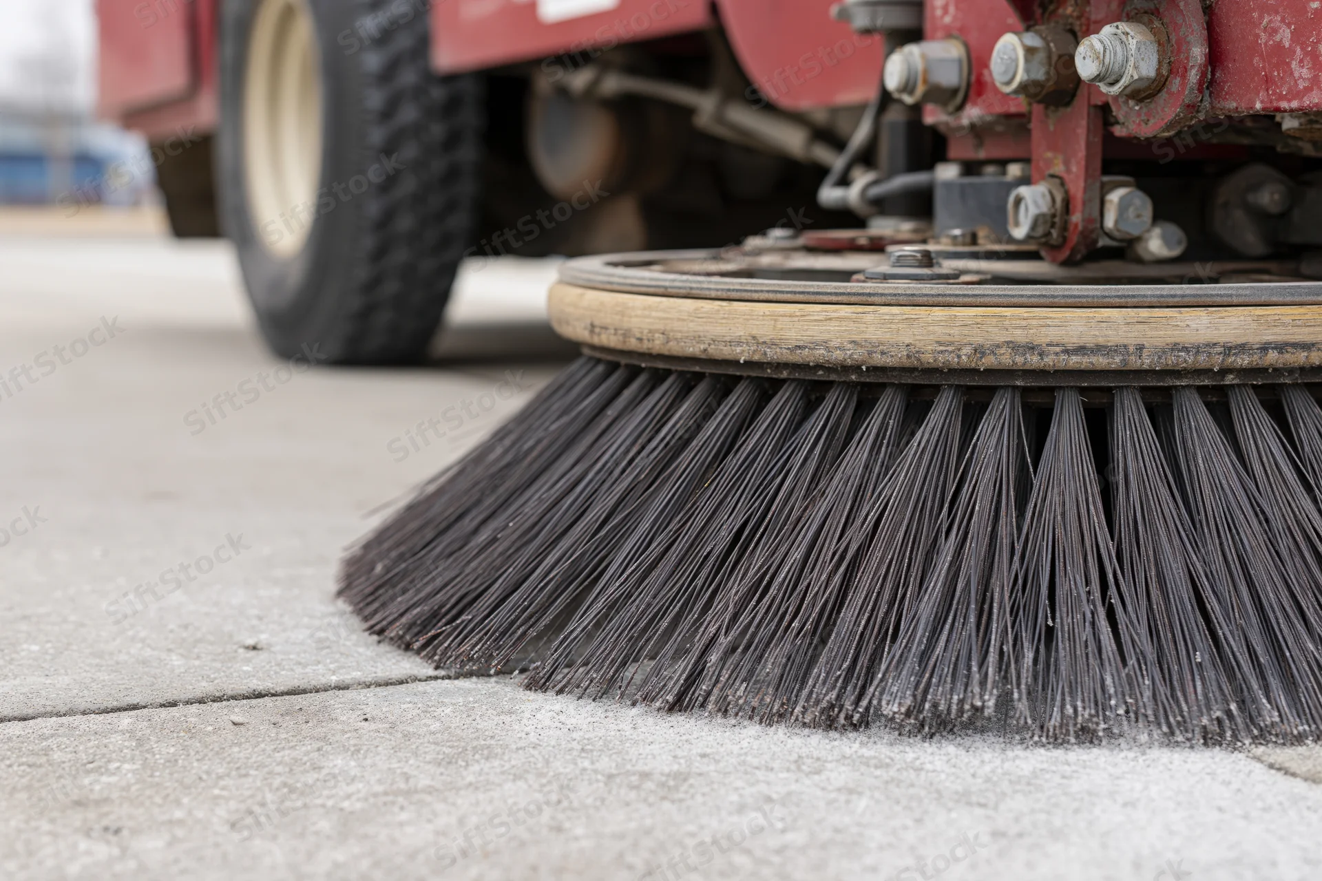 Close-up of circular brush on street sweeper machine cleaning pavement