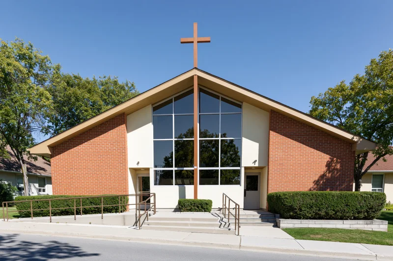 Suburban protestant church exterior with wooden cross on brick facade under clear blue sky