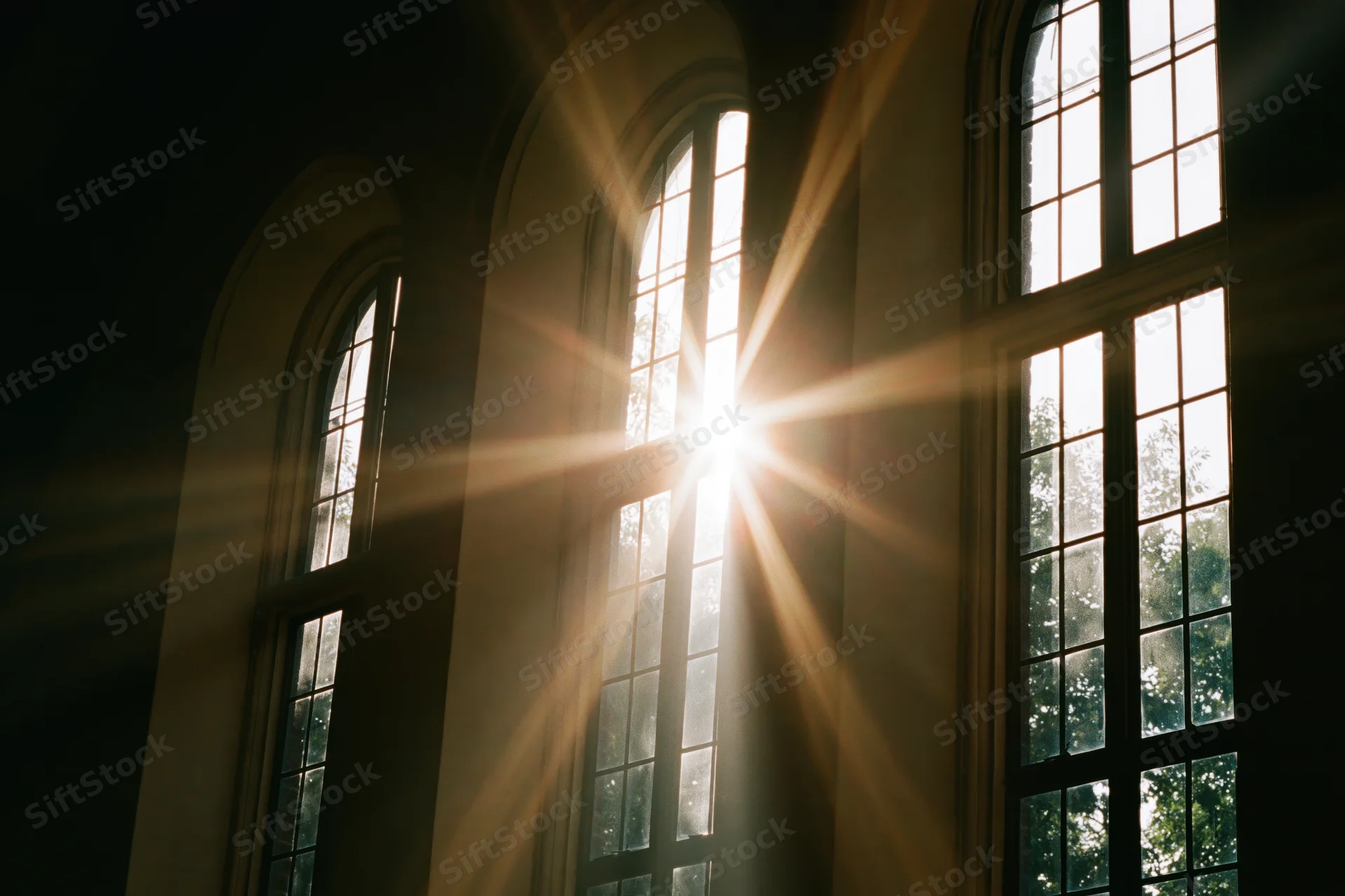 Sunlight bursting through tall arched church windows casting beams inside the interior