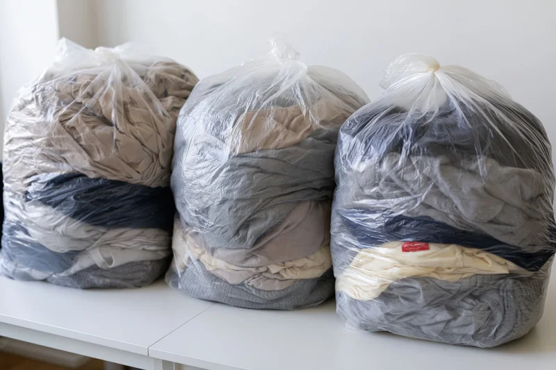 Three clear plastic bags filled with folded clothing arranged on a white table