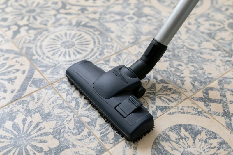 Vacuum cleaner head gliding across patterned ceramic floor tile