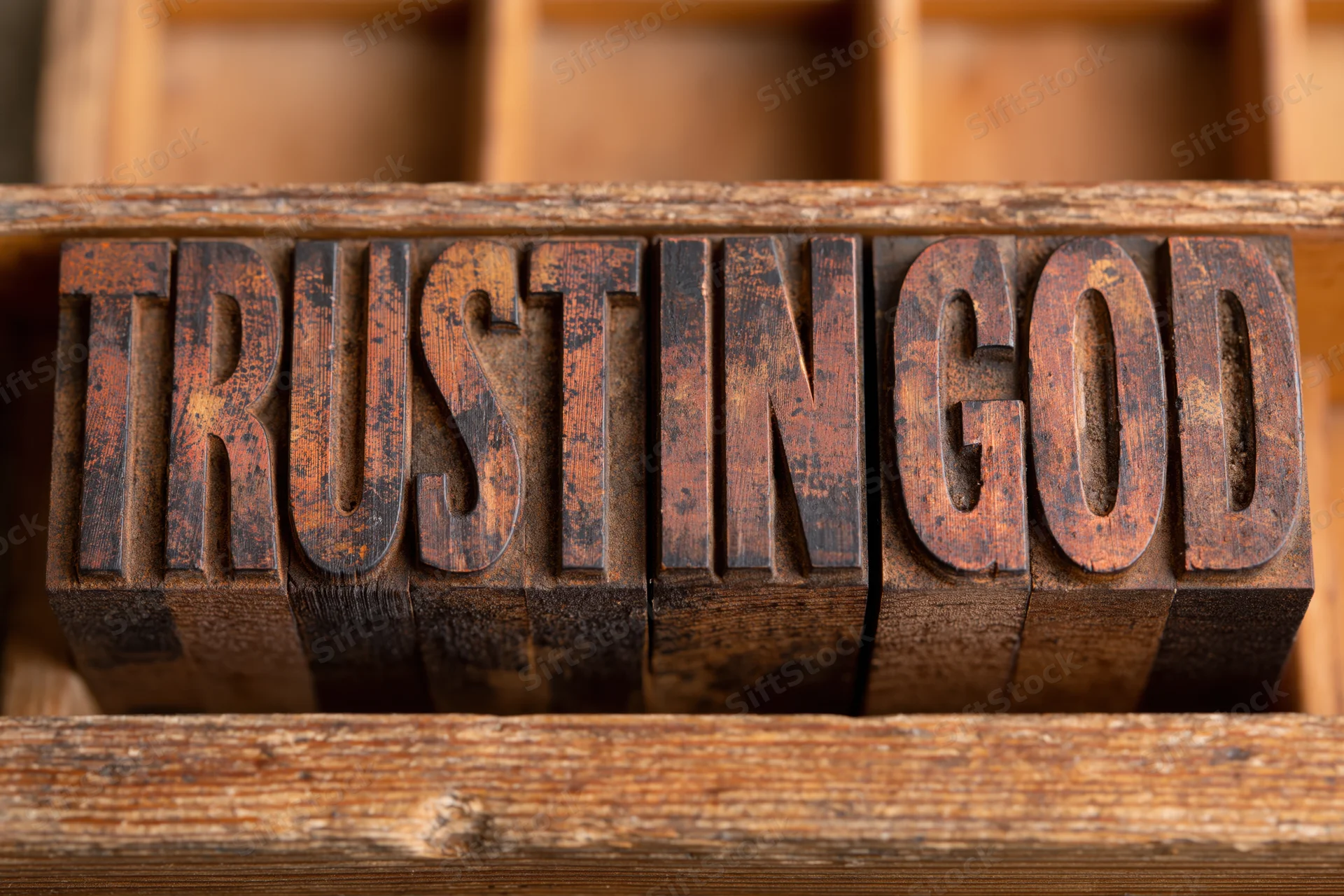 Wooden letterpress blocks spelling trust in god arranged in a tray