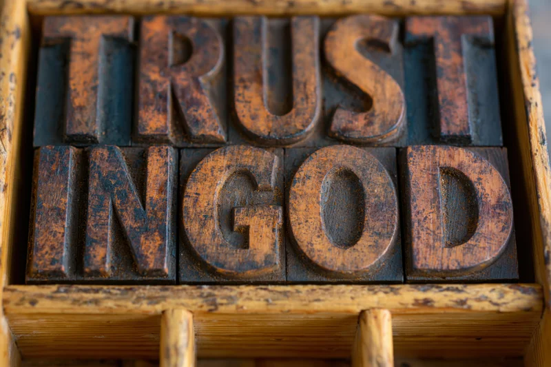 Vintage wooden letterpress blocks spelling trust in god arranged in a tray