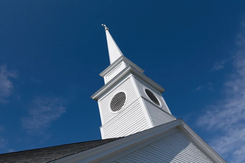 White church steeple with cross against blue sky