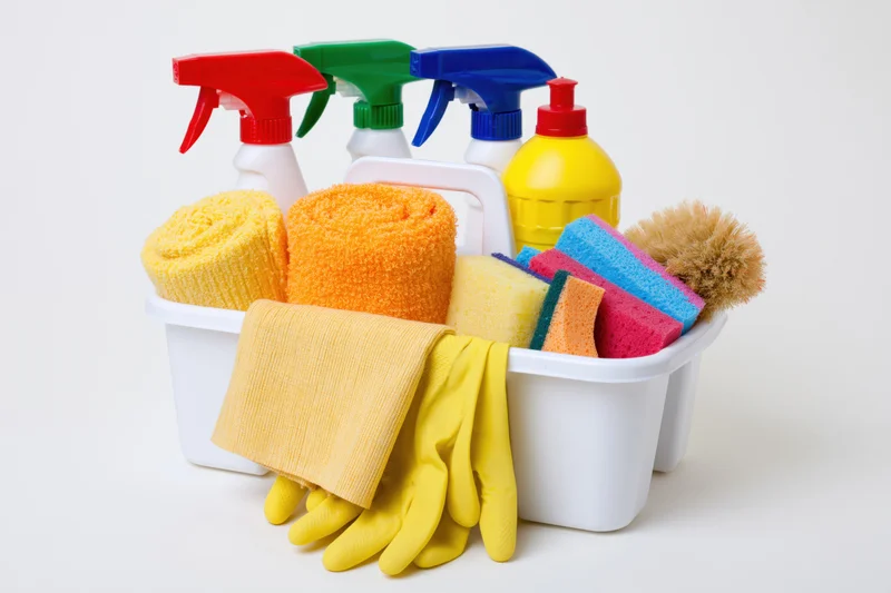 White plastic caddy filled with colorful cleaning supplies and tools on plain background