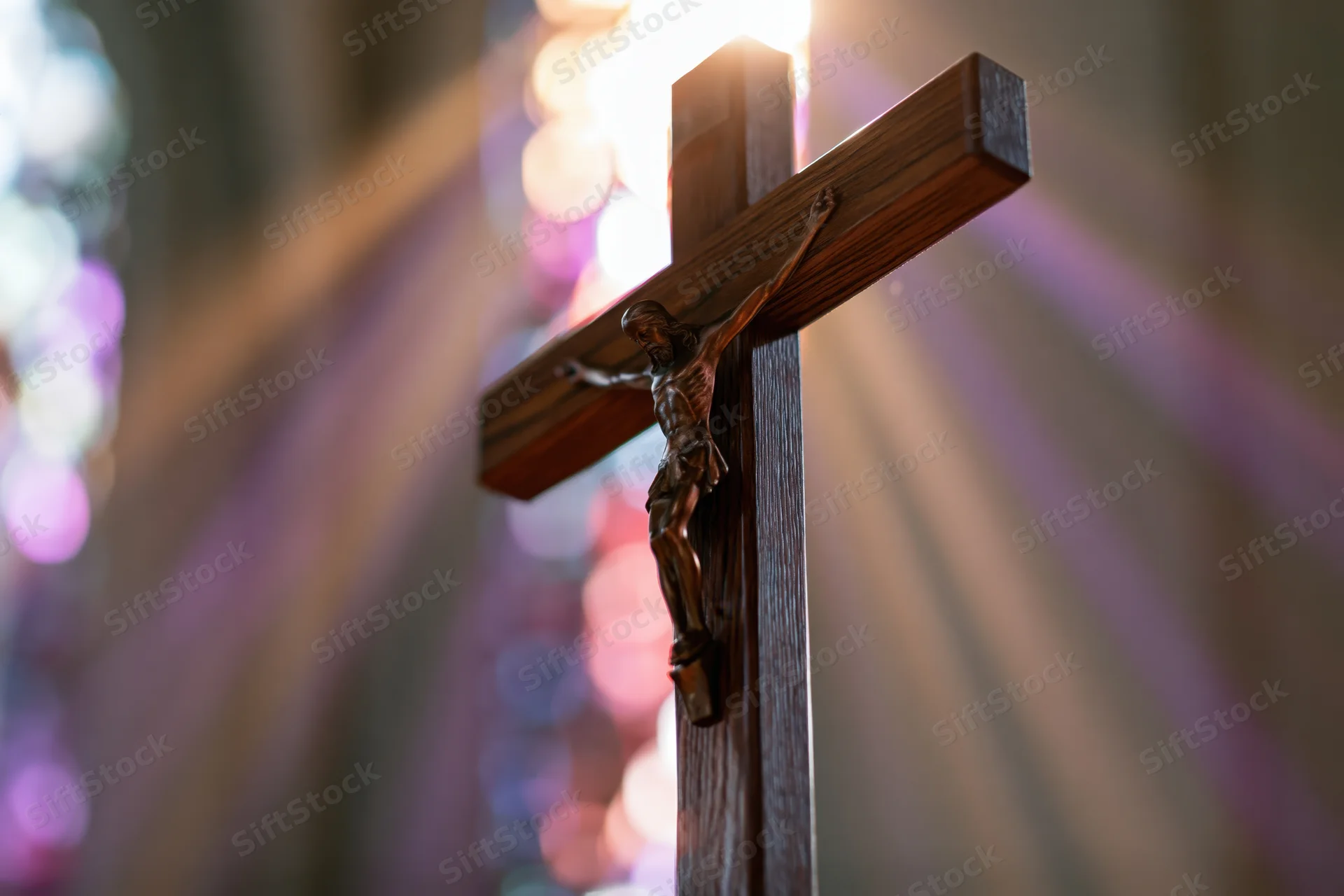 Wooden crucifix with jesus figure illuminated by light rays inside a church