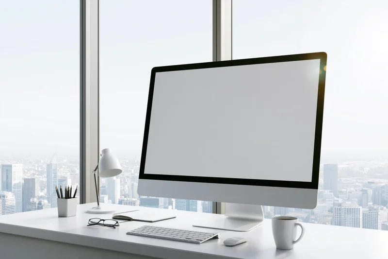 All-in-one computer on a white desk with city view through large window
