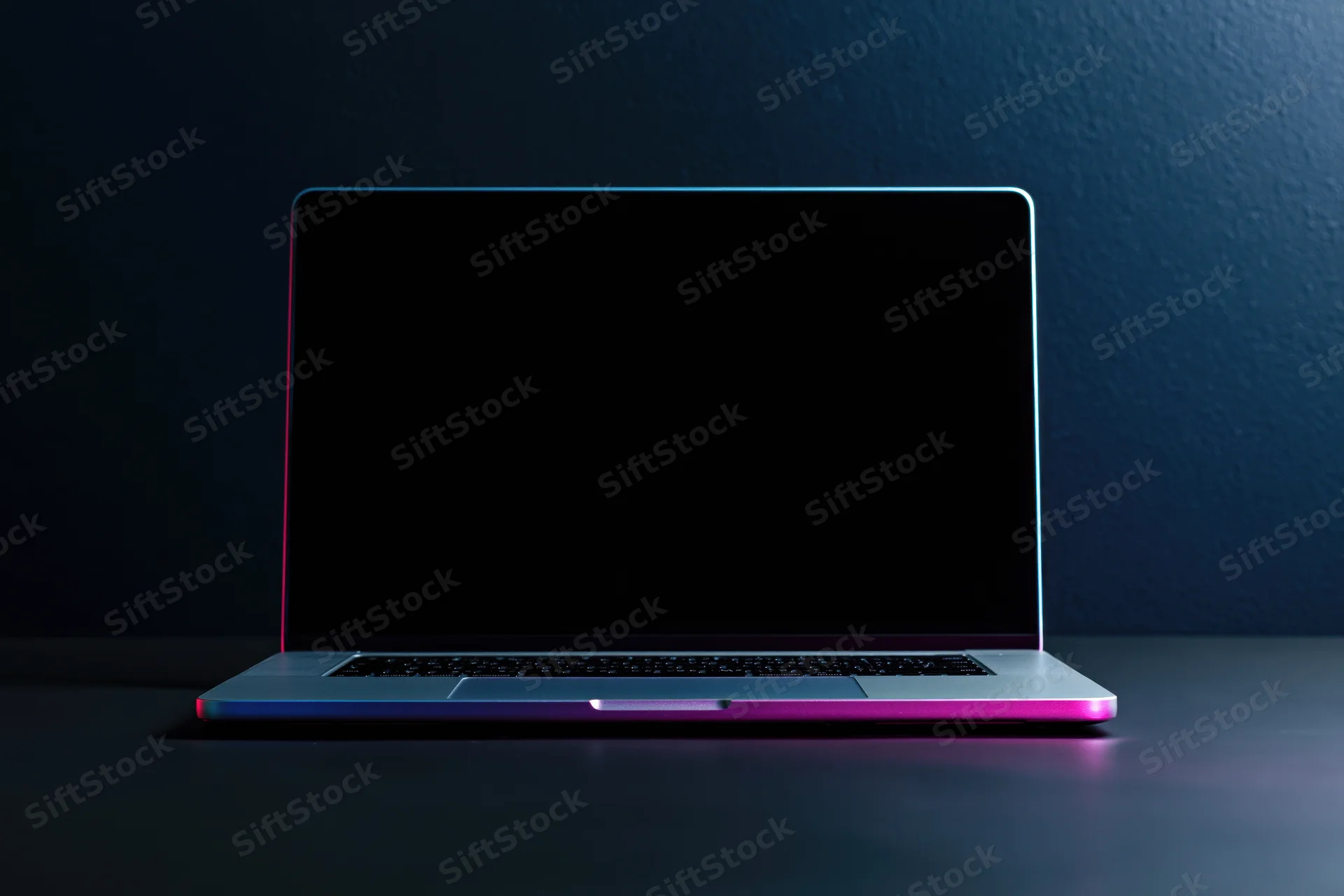 Silver laptop with blank screen and neon glow on dark surface
