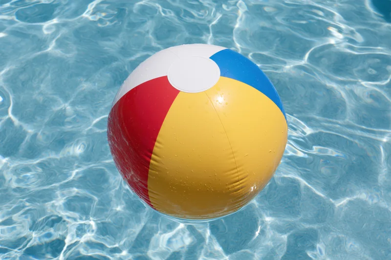 Colorful inflatable beach ball floating in clear blue pool water