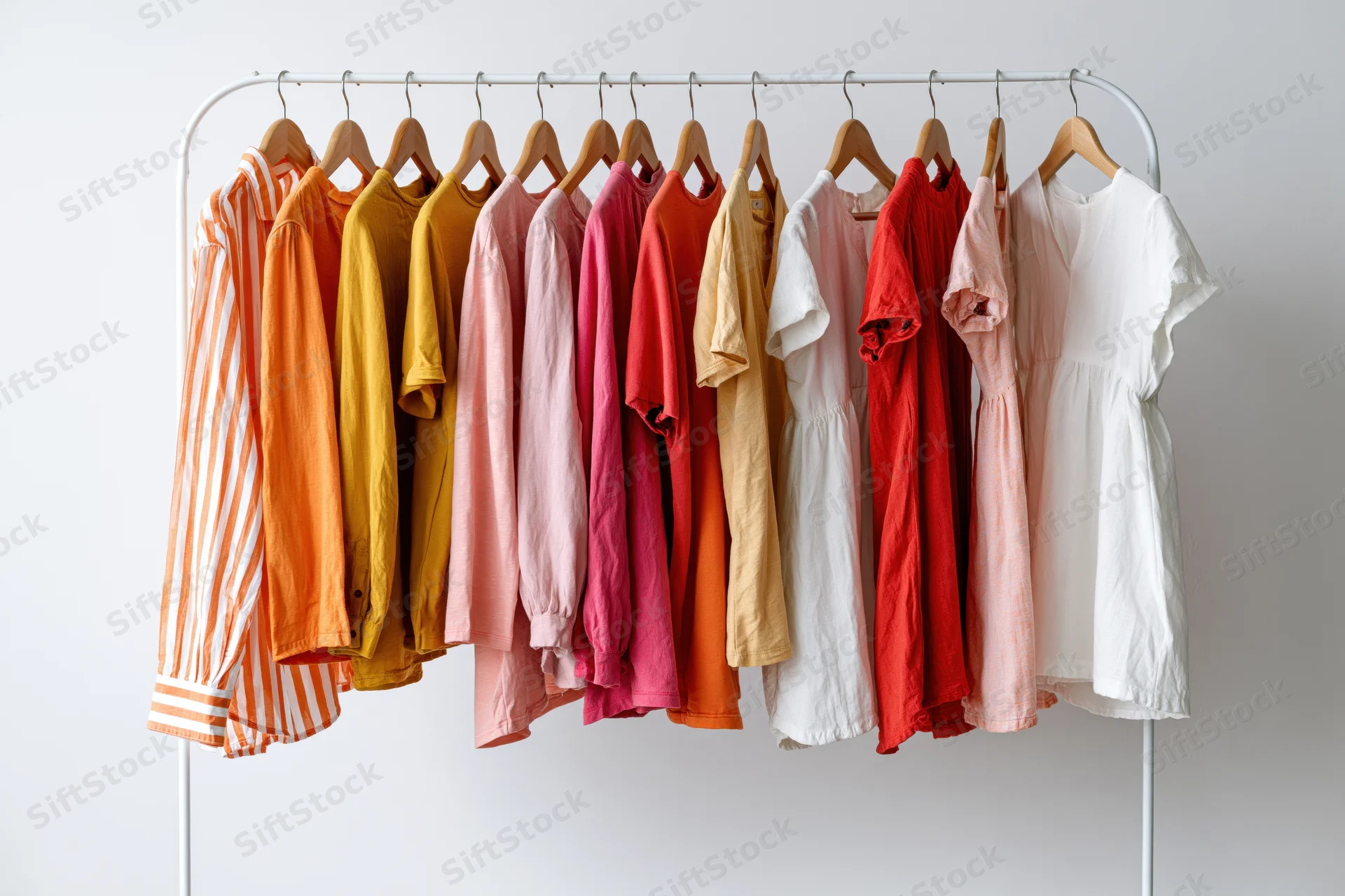 Colorful women's clothing hanging on a white metal rack in a bright studio space