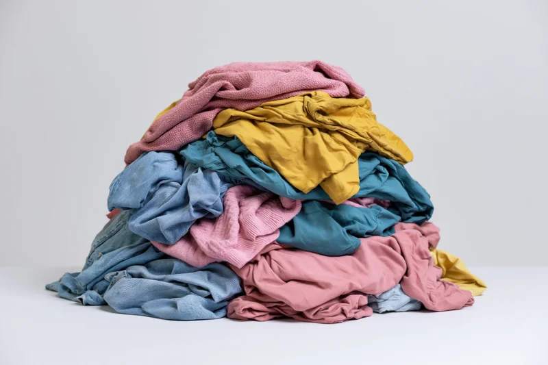 A messy pile of mixed clothing heaped on a white surface