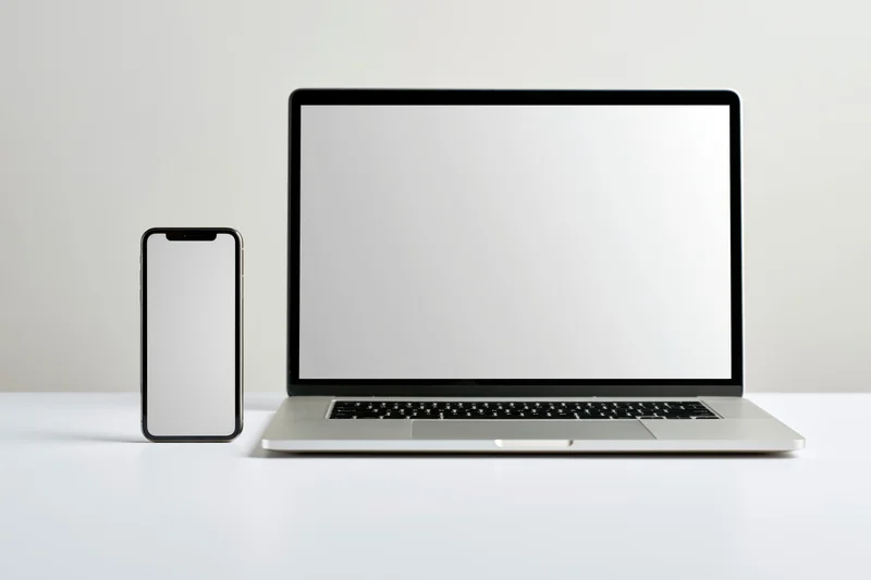 Laptop and smartphone with blank screens on a white desk