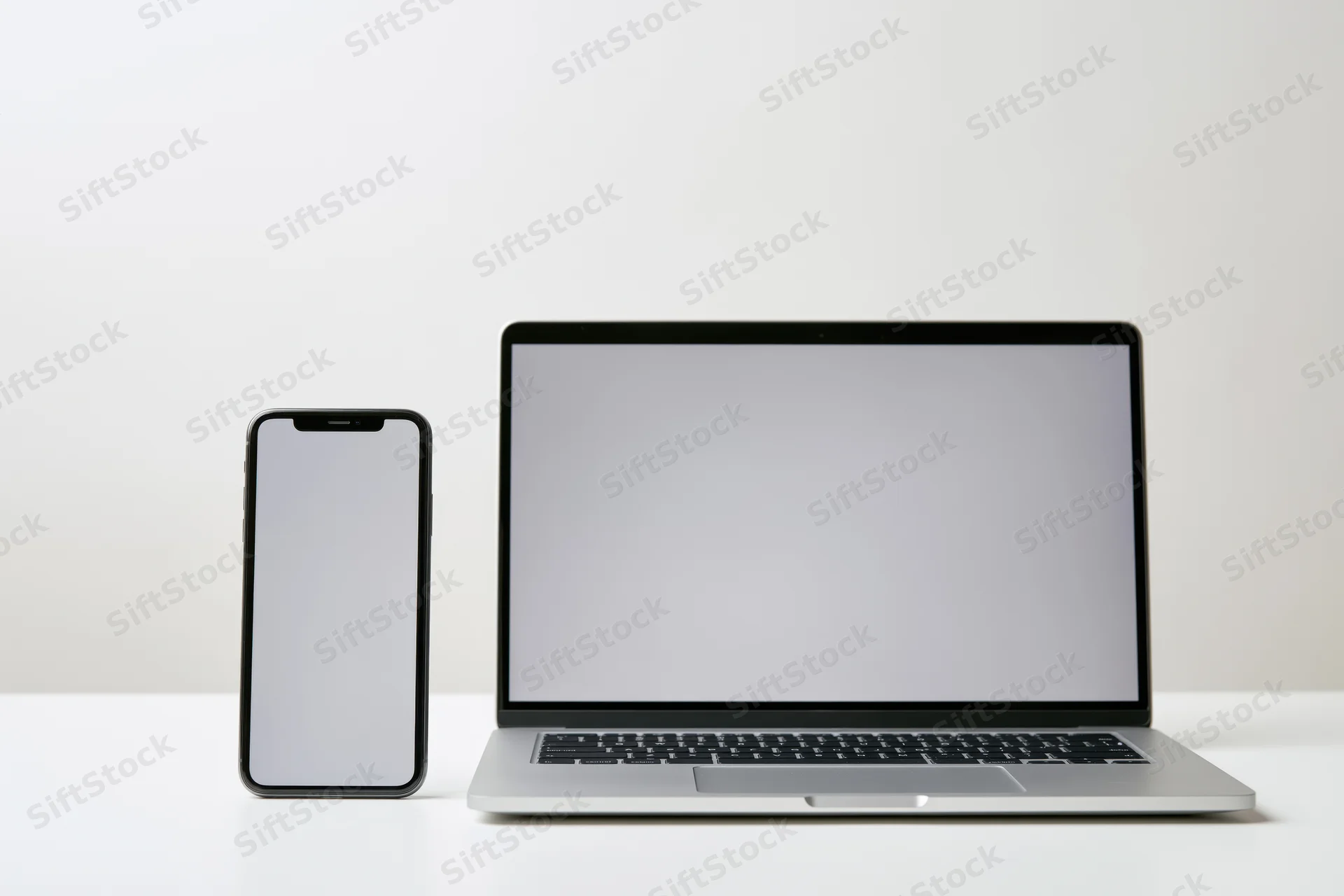 Modern smartphone and laptop side by side on a white surface