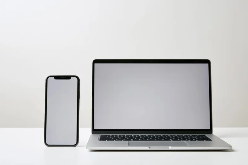 Modern smartphone and laptop side by side on a white surface