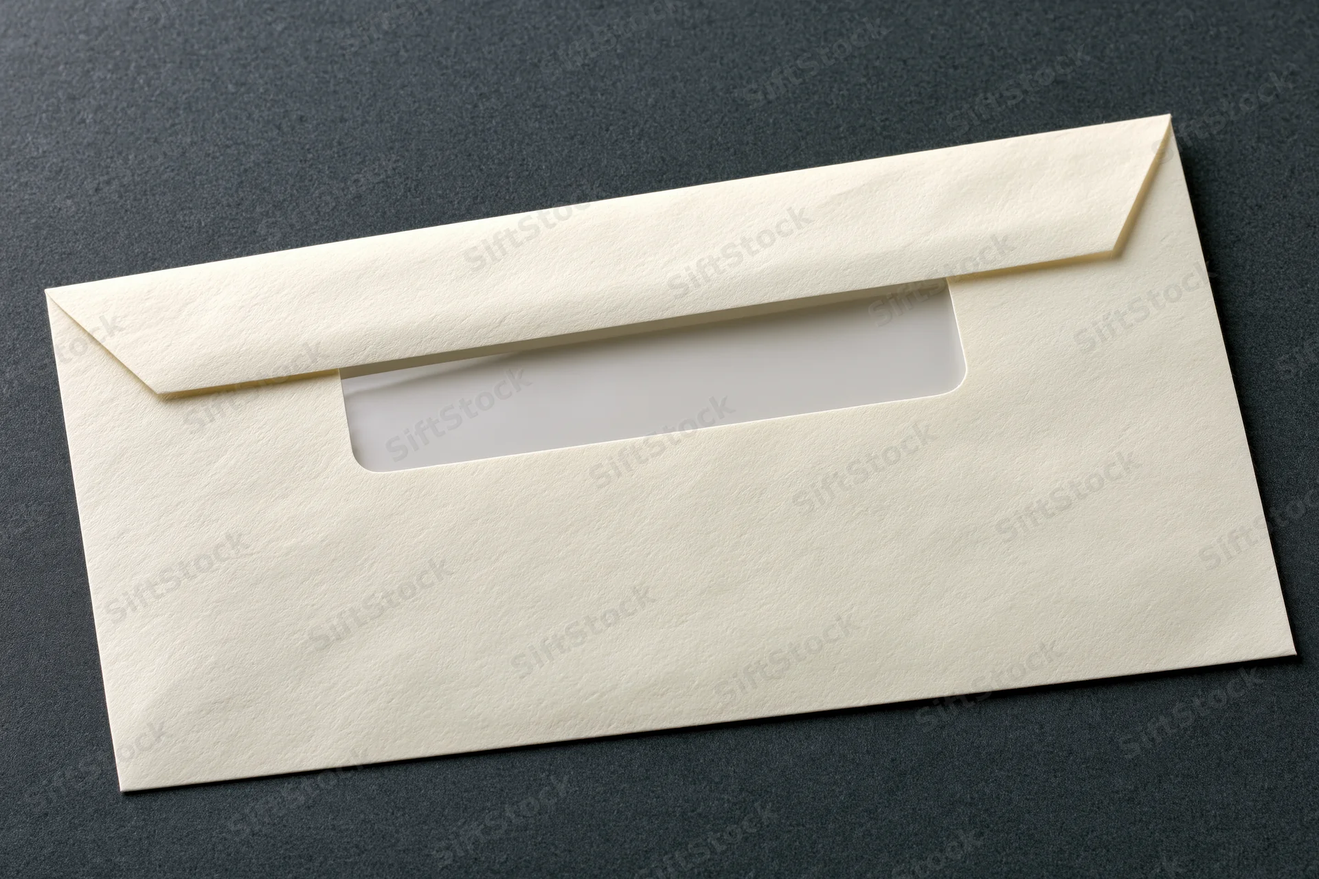 Cream-colored business envelope with window flap lying flat on dark textured surface
