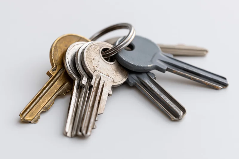 Four assorted keys on a metal split ring fanned out on a white surface