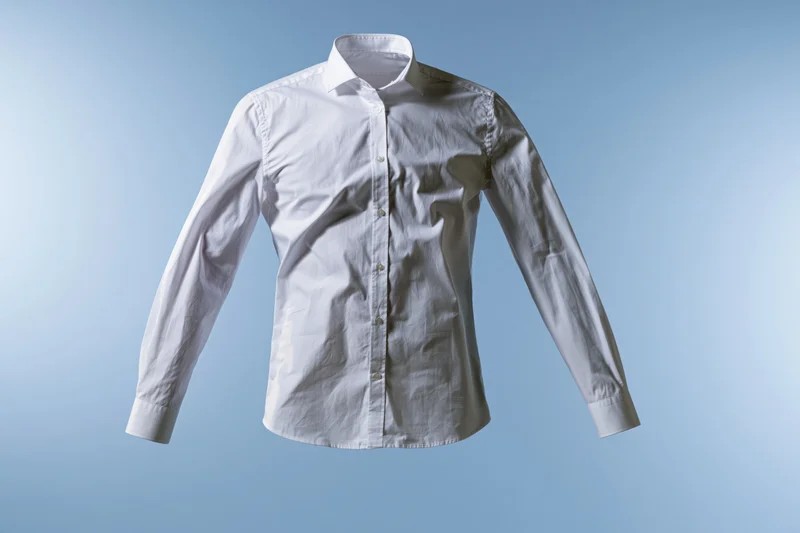 White long-sleeve button-up dress shirt floating mid-air against a light blue background