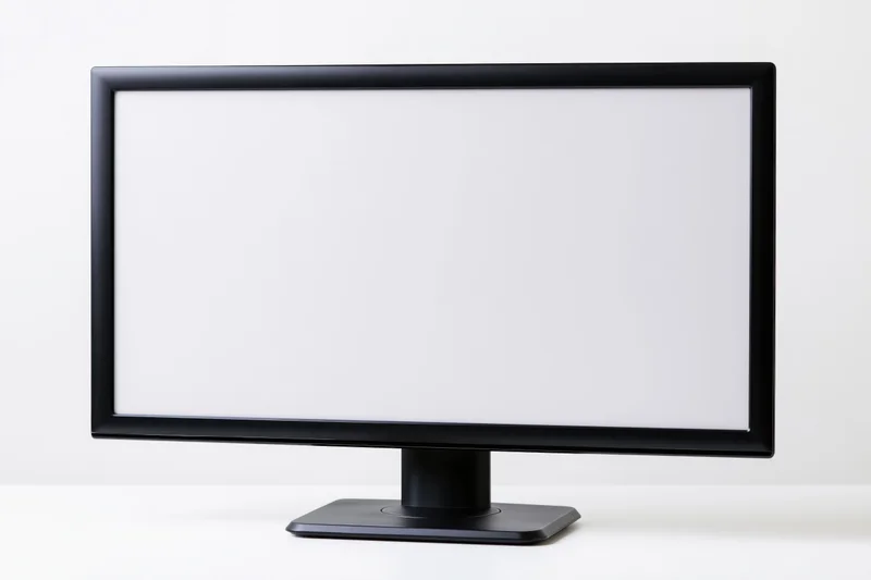Widescreen desktop computer monitor with blank white screen on white surface