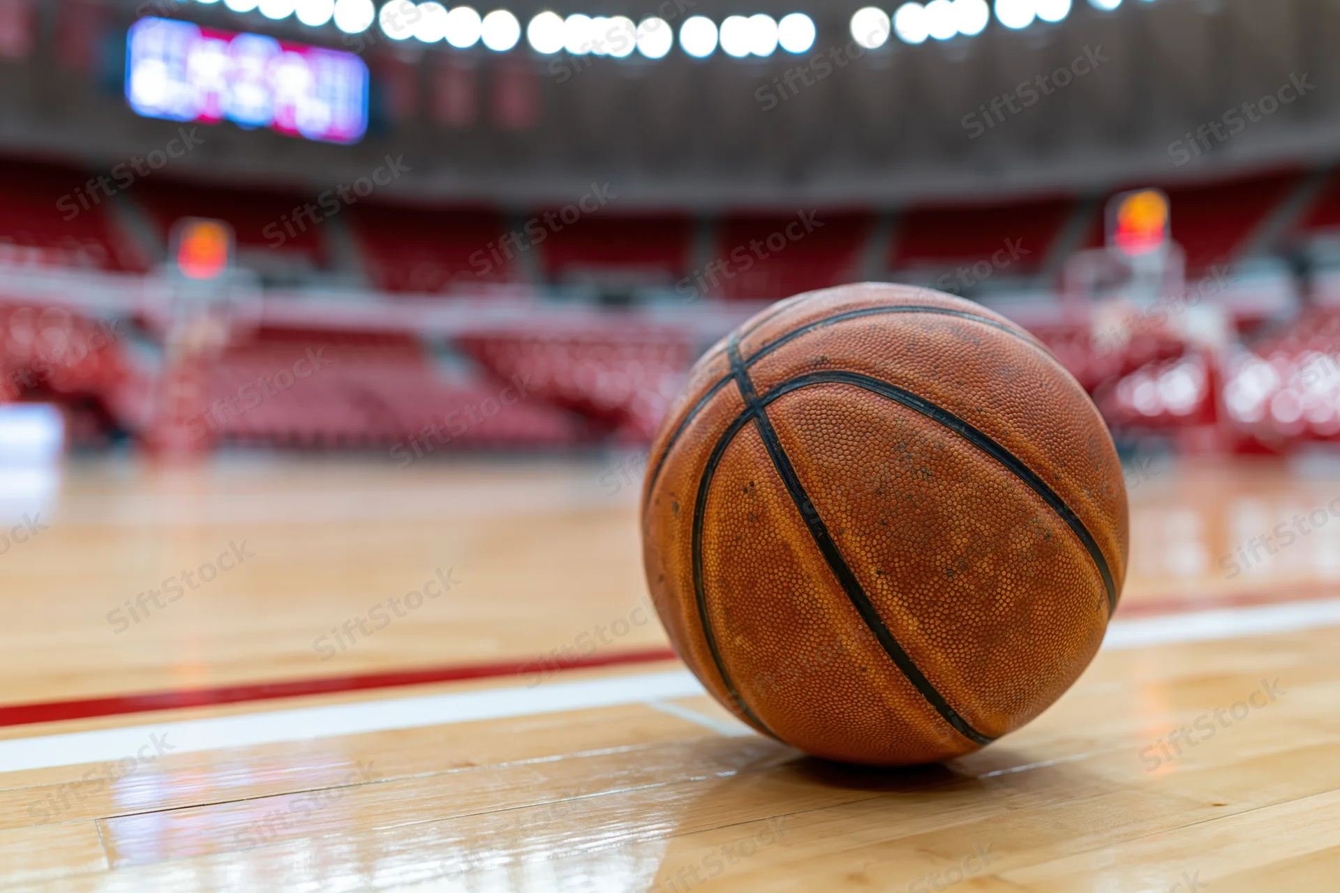 Worn leather basketball resting on painted court line in indoor arena