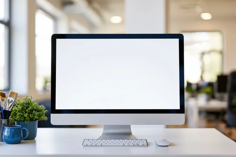 All-in-one desktop computer with blank white screen on office desk beside plant and art supplies