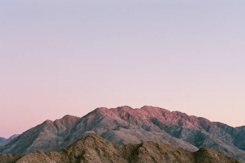 Arid mountain ridgeline with jagged rocky peaks under dusky sky