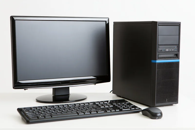 Black desktop computer tower with blue accent stripe, monitor, keyboard and mouse on white surface