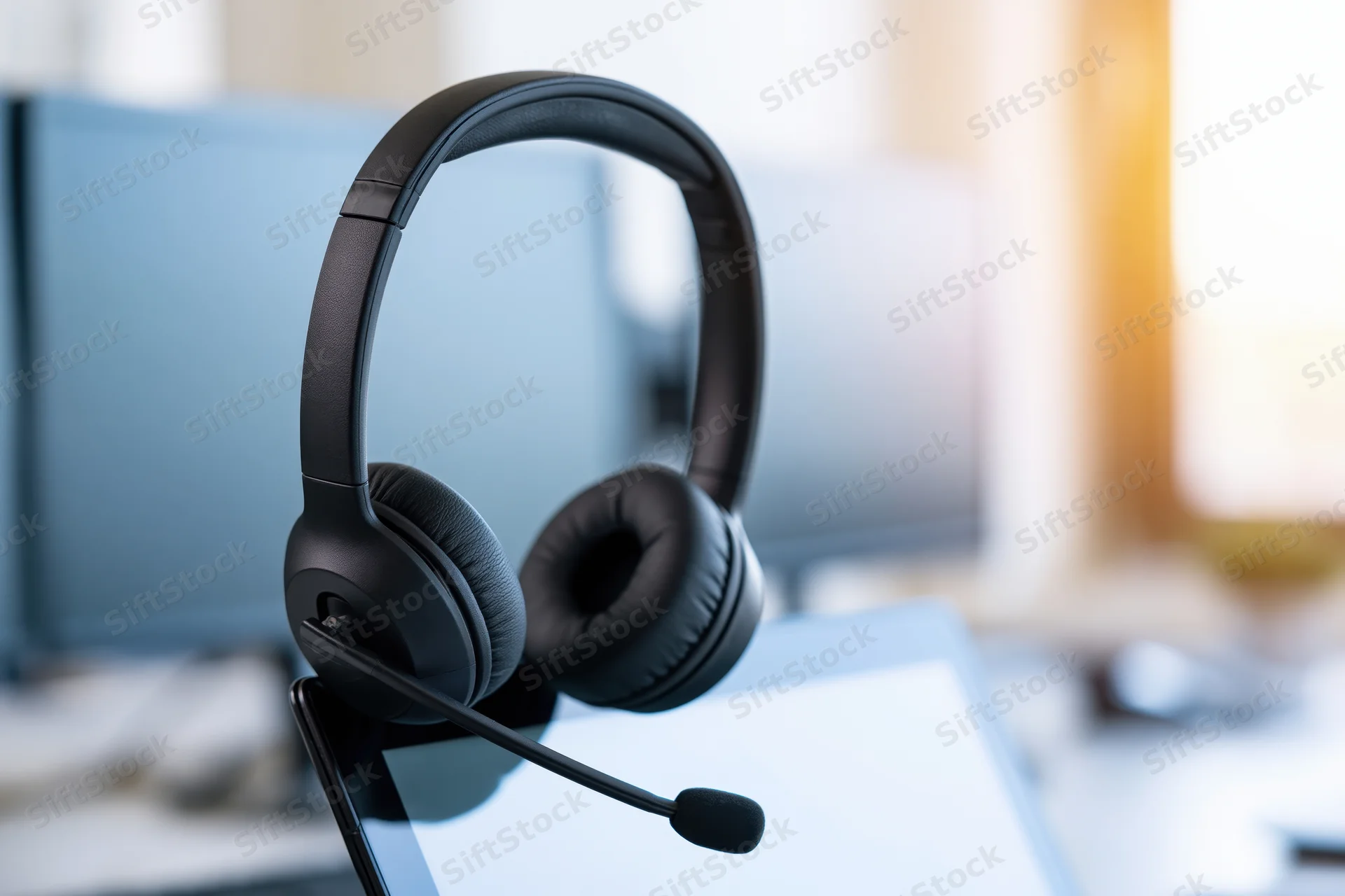 Black over-ear headset with boom microphone resting on laptop in office setting
