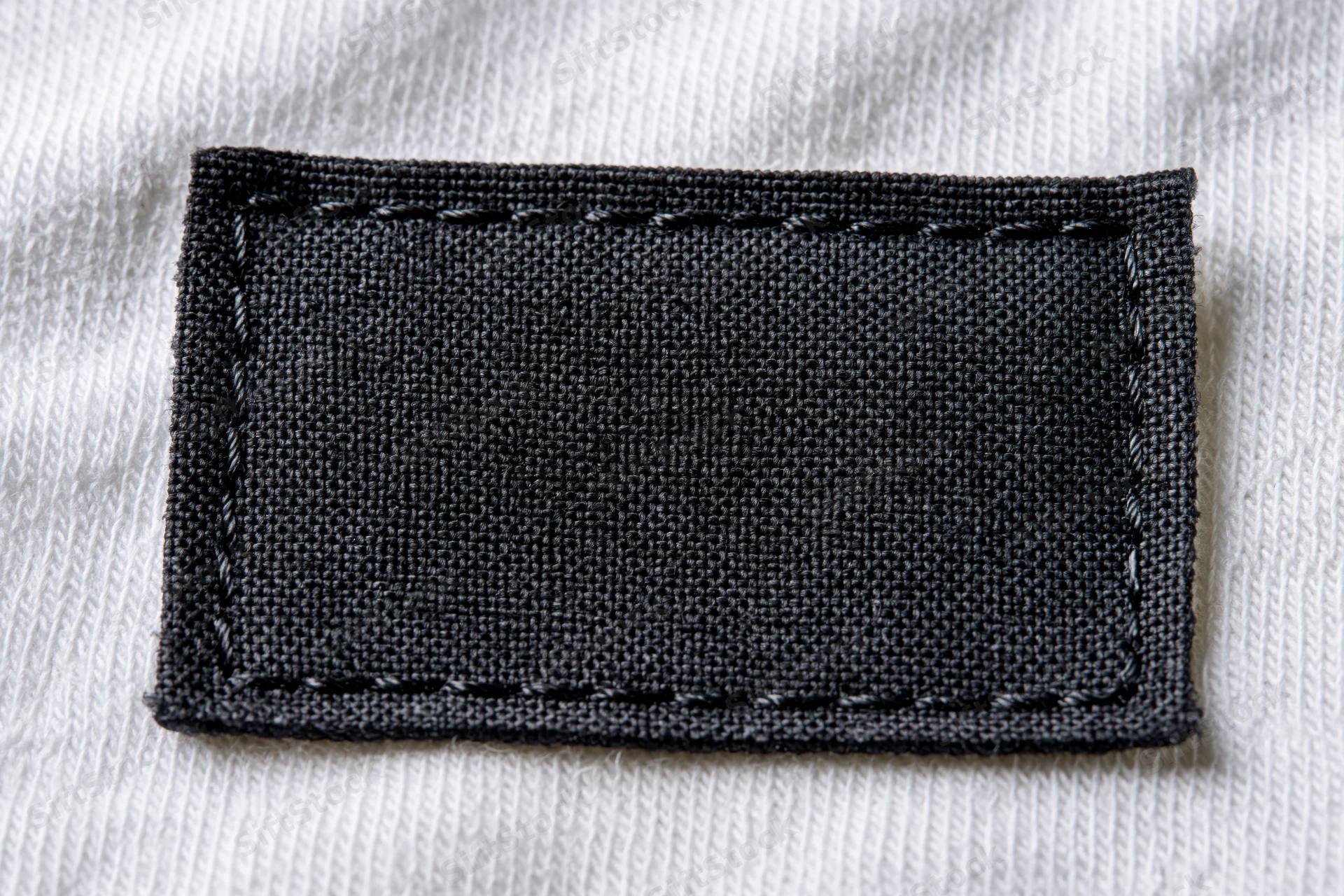 Blank black fabric label stitched onto white textile garment