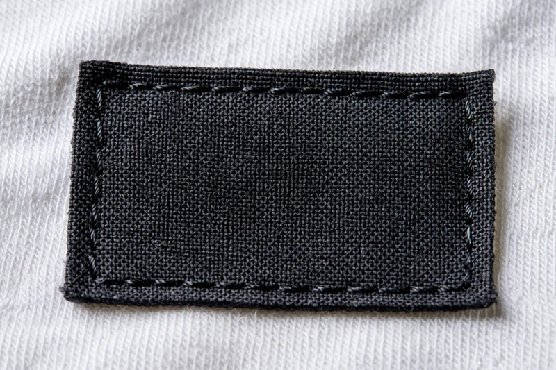 Blank black fabric label stitched onto white textile garment