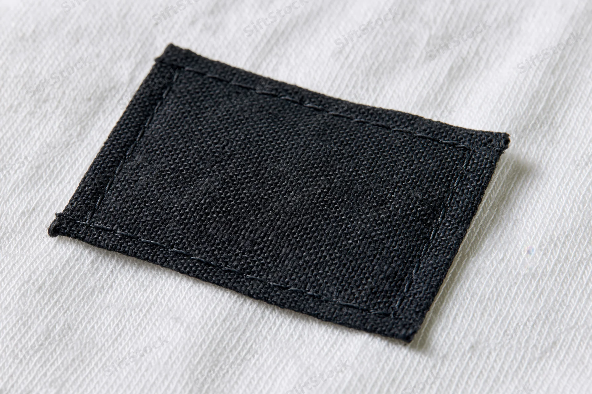 Black fabric label stitched onto white textile garment