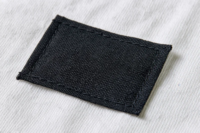 Black fabric label stitched onto white textile garment