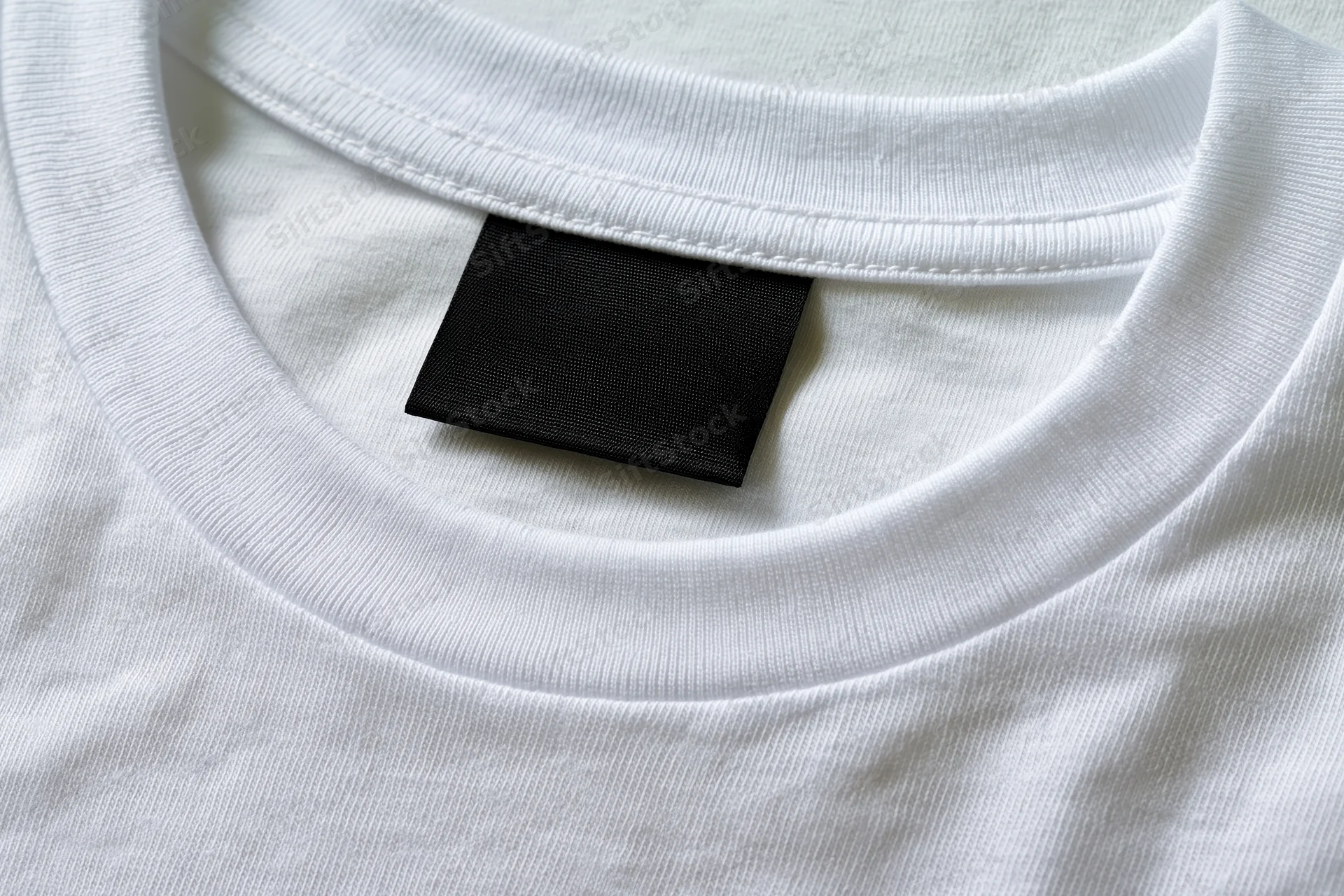 Close-up of blank black label sewn inside white t-shirt collar
