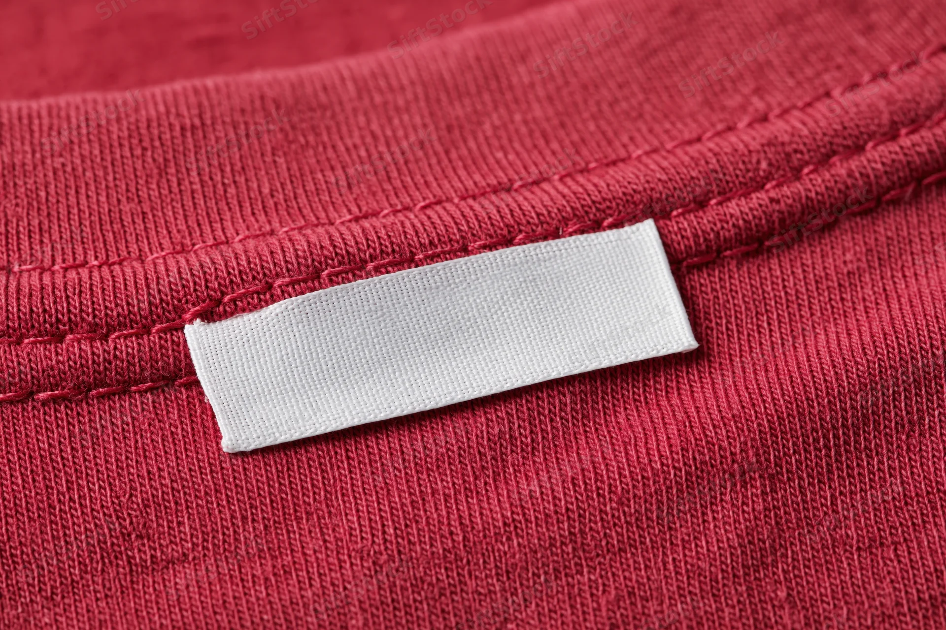 Blank white care label sewn into red garment collar