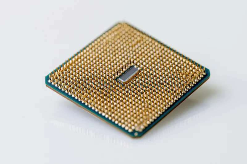 Cpu processor chip with gold pins viewed from below on white surface